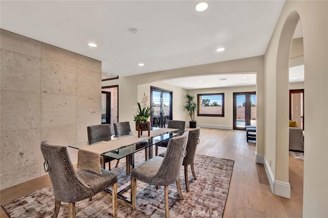 dining room with tile walls, light hardwood / wood-style flooring, and french doors