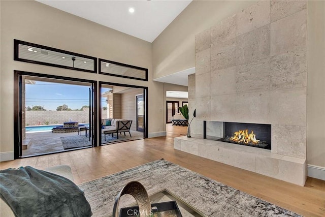 living room with high vaulted ceiling, wood-type flooring, and a tile fireplace