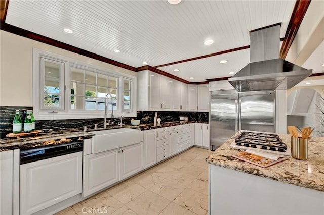 kitchen featuring dark stone counters, sink, tasteful backsplash, island range hood, and white cabinetry