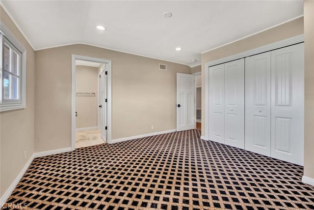 unfurnished bedroom featuring carpet, lofted ceiling, and a closet