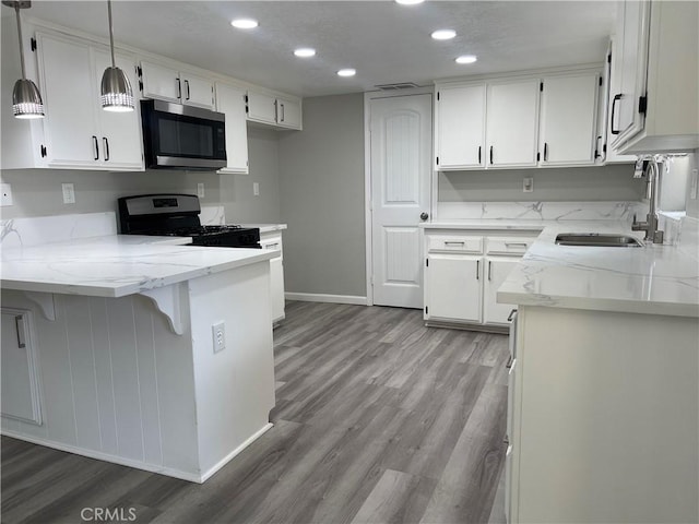 13165 Caspian Dr, Victorville, CA 92395 - kitchen featuring a peninsula, a sink, stainless steel microwave, baseboards, and range with gas stovetop