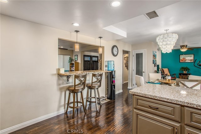 kitchen with a kitchen breakfast bar, a notable chandelier, decorative light fixtures, and dark hardwood / wood-style flooring