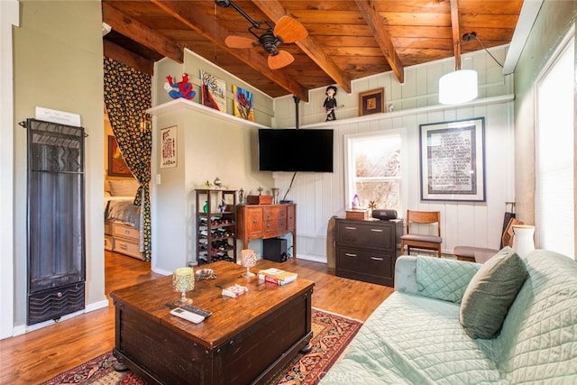 living area with wooden ceiling, a ceiling fan, beamed ceiling, and wood finished floors