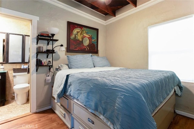 bedroom with light wood-style floors, ensuite bath, baseboards, and crown molding