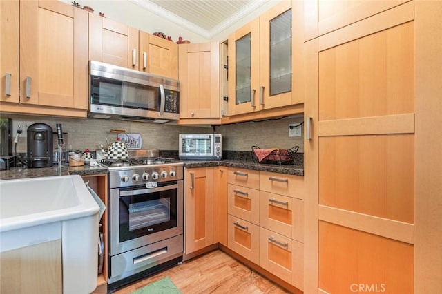 kitchen with appliances with stainless steel finishes, a toaster, ornamental molding, and decorative backsplash