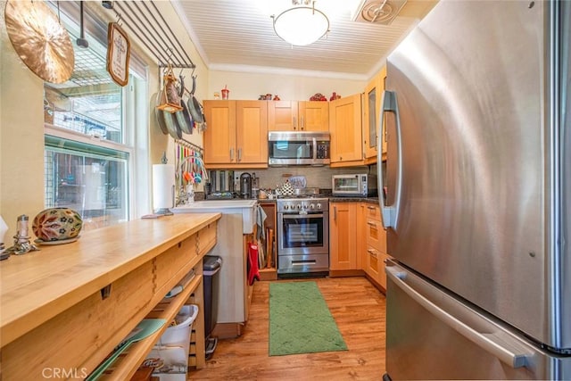 kitchen with light wood finished floors, a toaster, decorative backsplash, appliances with stainless steel finishes, and ornamental molding