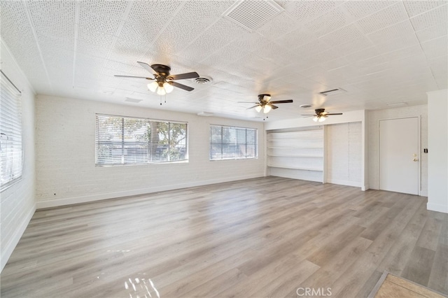 unfurnished living room with light hardwood / wood-style floors, brick wall, built in features, and ceiling fan