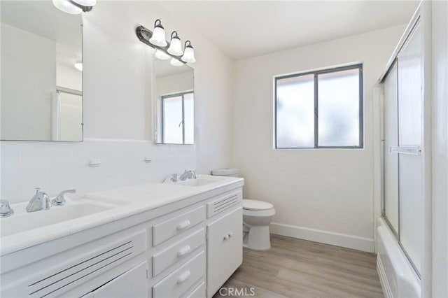 full bathroom with toilet, wood-type flooring, vanity, shower / bath combination with glass door, and tasteful backsplash