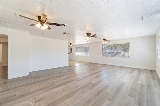 unfurnished living room with light hardwood / wood-style floors, brick wall, and ceiling fan