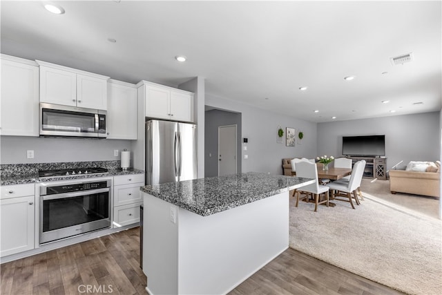 kitchen with white cabinetry, stainless steel appliances, dark stone countertops, and dark hardwood / wood-style floors