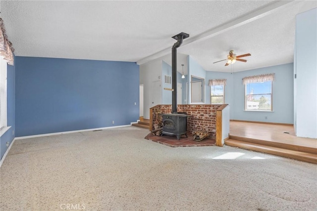 unfurnished living room with a wood stove, ceiling fan, baseboards, and lofted ceiling