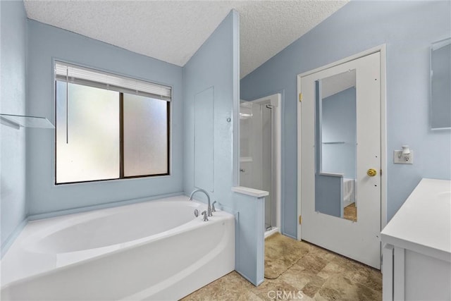 bathroom featuring a garden tub, a shower stall, a textured ceiling, and vanity