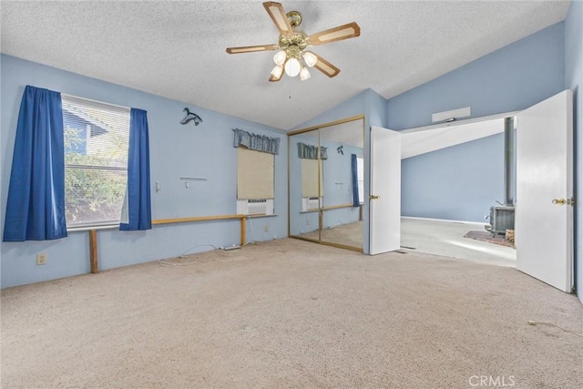 unfurnished bedroom featuring a closet, lofted ceiling, a wood stove, and a textured ceiling