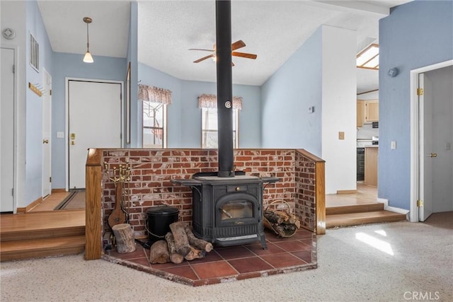 interior details with visible vents, a ceiling fan, a wood stove, a textured ceiling, and beverage cooler