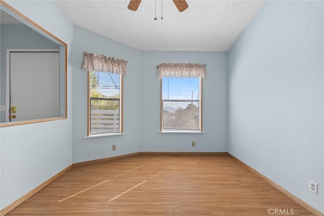 empty room featuring light wood-type flooring, ceiling fan, baseboards, and a textured ceiling