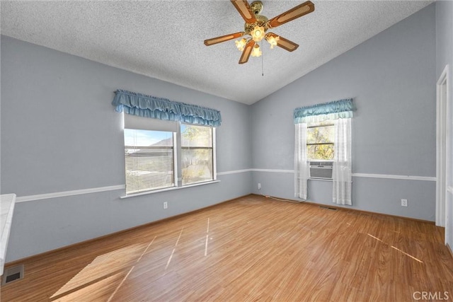 unfurnished room with lofted ceiling, wood finished floors, visible vents, and a healthy amount of sunlight