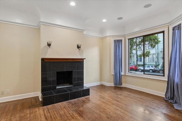 unfurnished living room featuring crown molding, a fireplace, and wood-type flooring