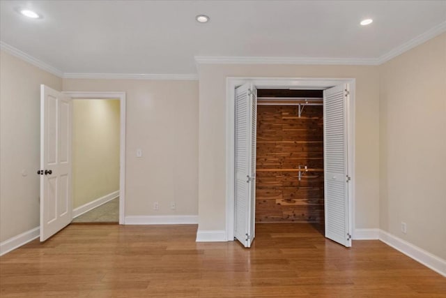 unfurnished bedroom with light wood-type flooring, a closet, and crown molding