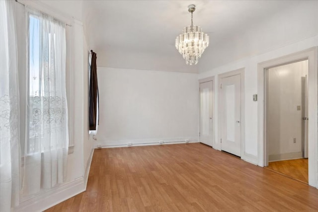 unfurnished bedroom featuring an inviting chandelier and light hardwood / wood-style floors