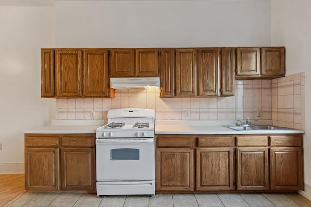 kitchen with gas range gas stove, backsplash, sink, and light tile patterned floors