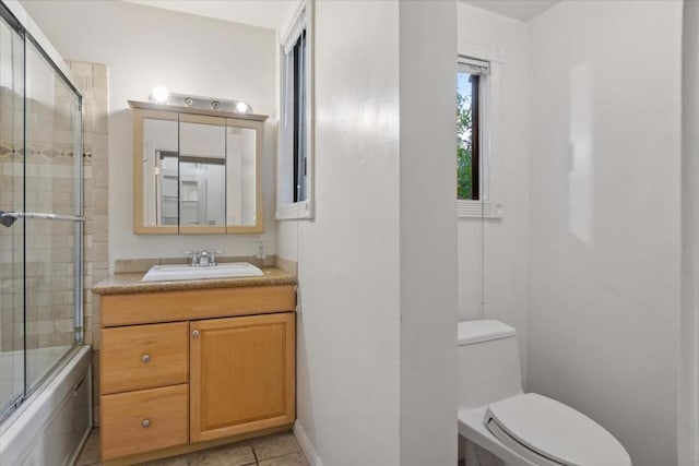 full bathroom featuring toilet, vanity, tile patterned floors, and bath / shower combo with glass door