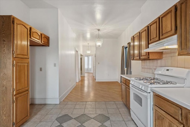 kitchen with hanging light fixtures, gas range gas stove, tasteful backsplash, and light tile patterned flooring