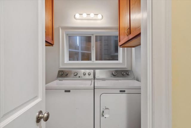 clothes washing area featuring washer and clothes dryer and cabinets