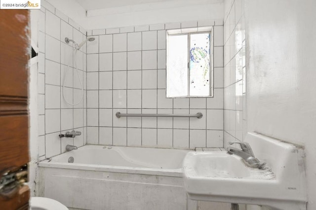 full bathroom with tiled shower / bath combo, toilet, and sink