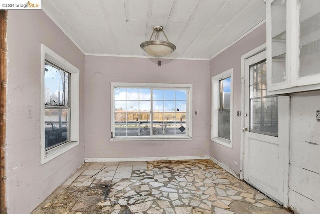 unfurnished dining area with plenty of natural light and crown molding