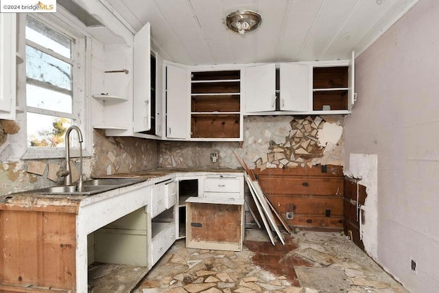 kitchen featuring decorative backsplash, white cabinetry, and sink