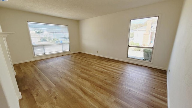 spare room with a textured ceiling, light hardwood / wood-style flooring, and a wealth of natural light