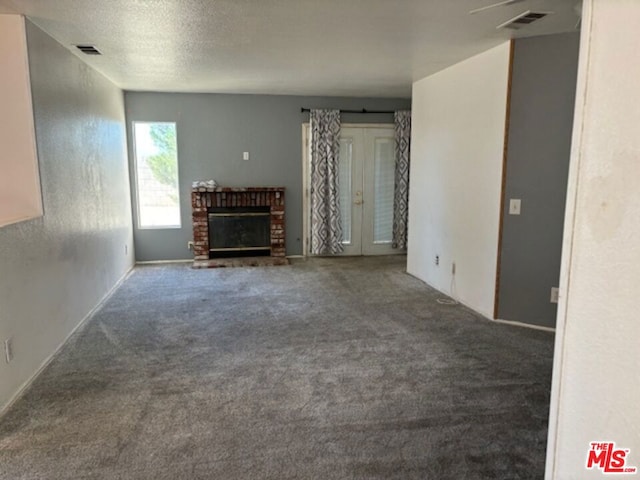 unfurnished living room featuring a textured ceiling, carpet floors, and a fireplace