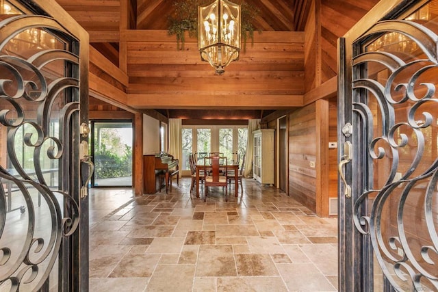 entryway with wood walls, french doors, a high ceiling, and an inviting chandelier