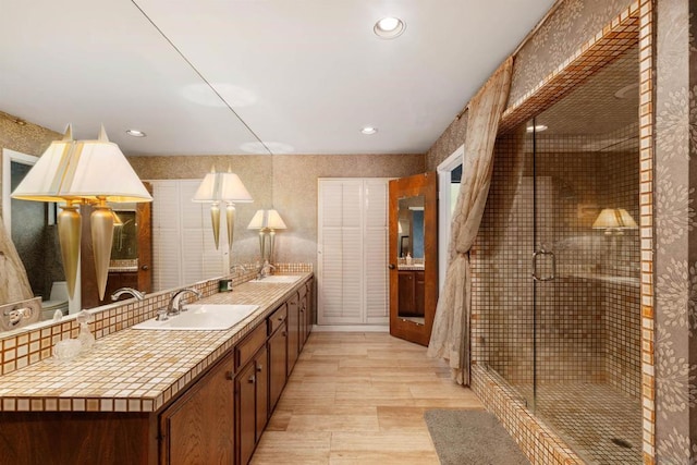 bathroom with vanity, a shower with shower door, and wood-type flooring