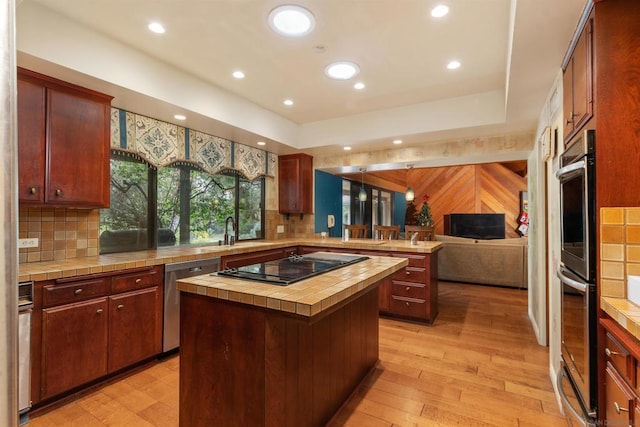 kitchen featuring stainless steel appliances, light hardwood / wood-style flooring, backsplash, tile countertops, and a kitchen island