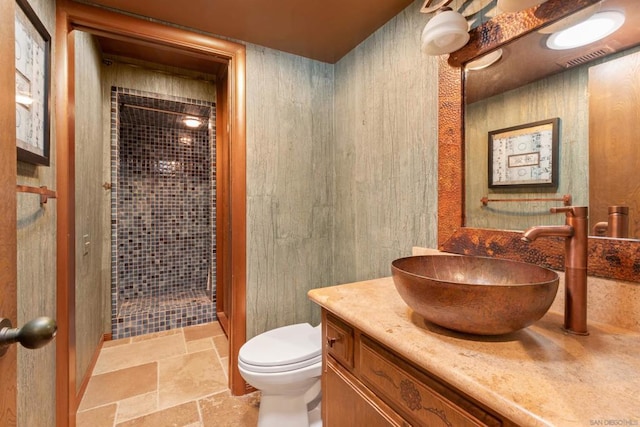 bathroom with vanity, toilet, and tiled shower