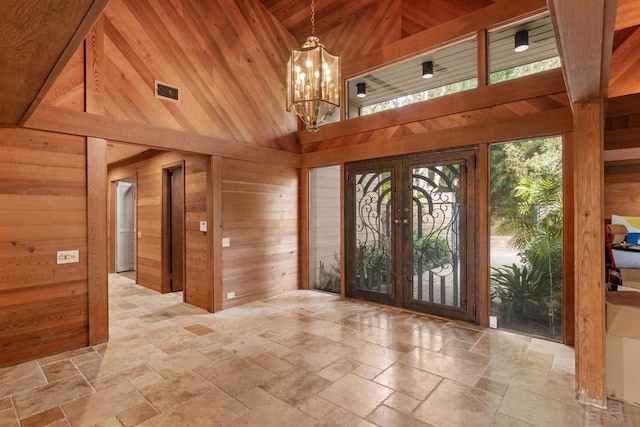 foyer entrance featuring wood walls, high vaulted ceiling, and french doors