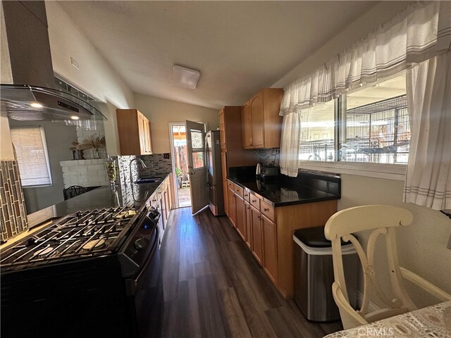 kitchen with black stove, stainless steel refrigerator, dark hardwood / wood-style floors, range hood, and sink