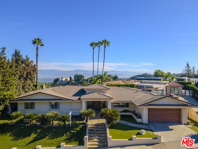 ranch-style home with a mountain view, a garage, and a front lawn