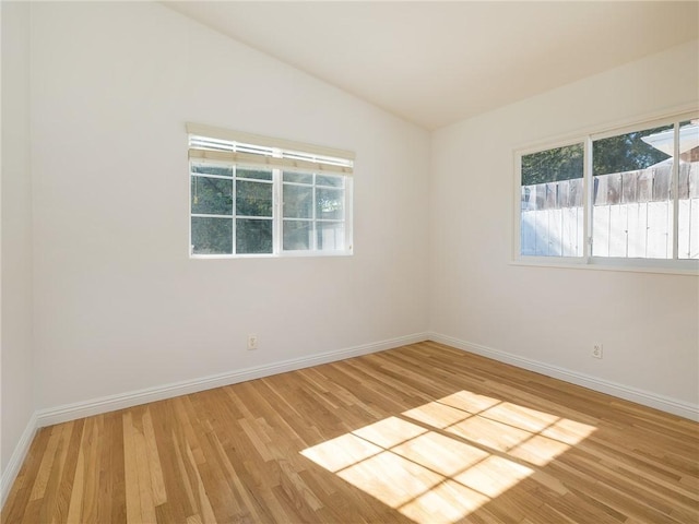 spare room featuring wood-type flooring and vaulted ceiling