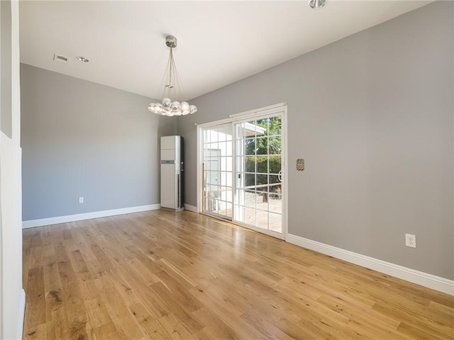 empty room featuring light hardwood / wood-style flooring and a chandelier