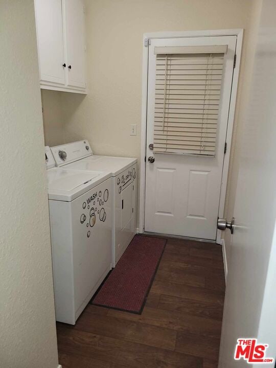 laundry area featuring washing machine and clothes dryer, dark hardwood / wood-style floors, and cabinets