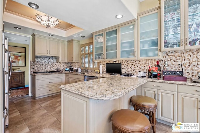 kitchen featuring kitchen peninsula, a breakfast bar, light stone countertops, appliances with stainless steel finishes, and tasteful backsplash