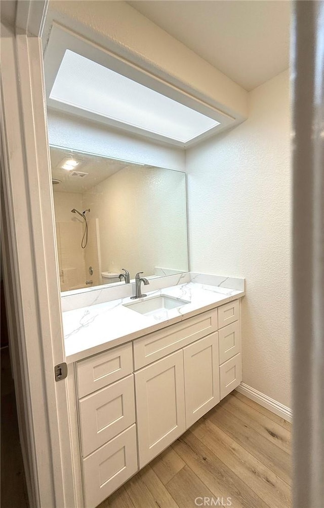 bathroom with hardwood / wood-style floors, vanity, and walk in shower