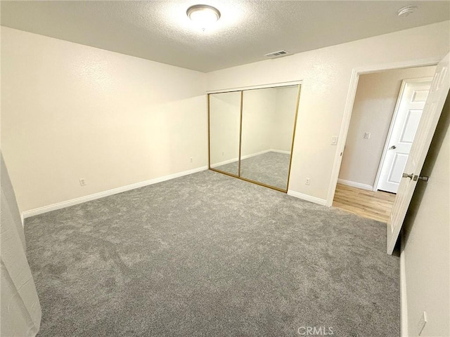 unfurnished bedroom with carpet floors, a textured ceiling, and a closet