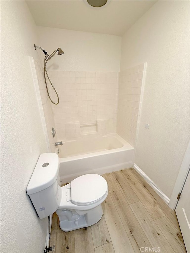 bathroom featuring hardwood / wood-style flooring, toilet, and bathing tub / shower combination