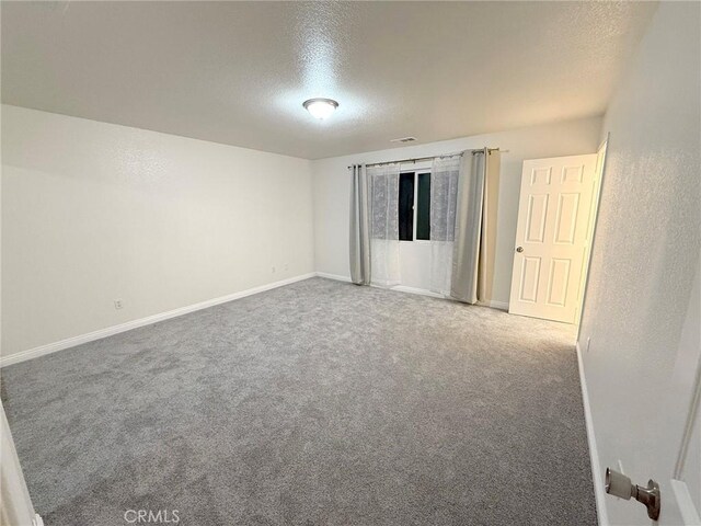 unfurnished room featuring carpet flooring and a textured ceiling