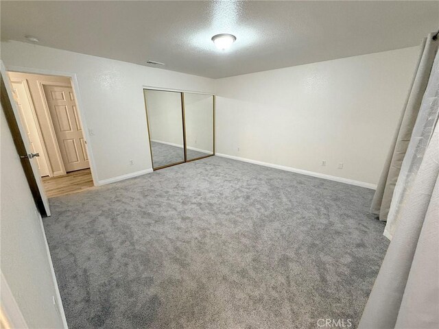 unfurnished bedroom with carpet flooring, a closet, and a textured ceiling