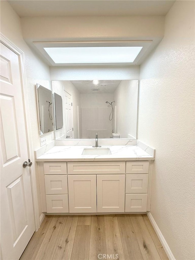 bathroom with a shower, wood-type flooring, and a skylight