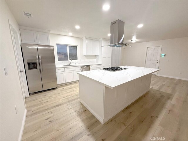 kitchen featuring sink, a kitchen island, white cabinetry, island exhaust hood, and stainless steel appliances